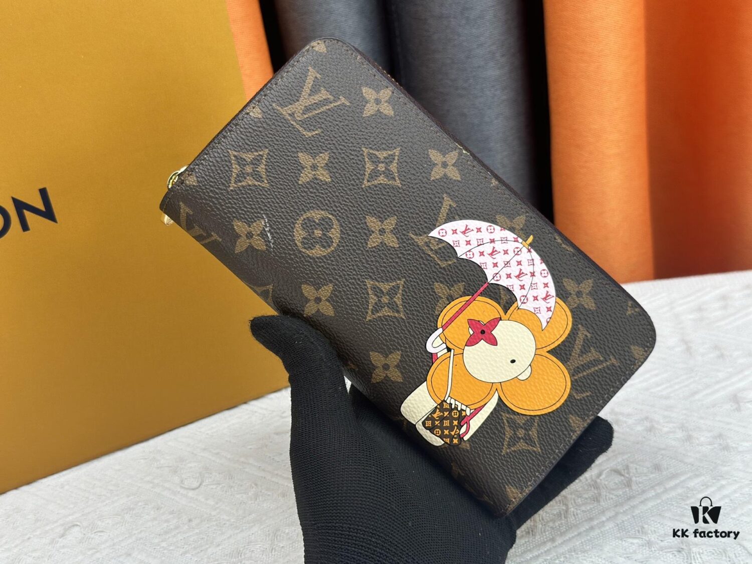 Wallet M60017 Umbrella M80857 M81544 This collectible multicolored zip-around wallet is crafted from Monogram canvas from the Vivienne Holidays 2022 collection, featuring an exquisite print of Louis Vuitton's mascot Vivienne standing in front of the brand's avant-garde Tokyo boutique with Japan's iconic Mount Fuji in the background. This vibrant high-end wallet serves as an invitation to journey and makes a perfect gift.