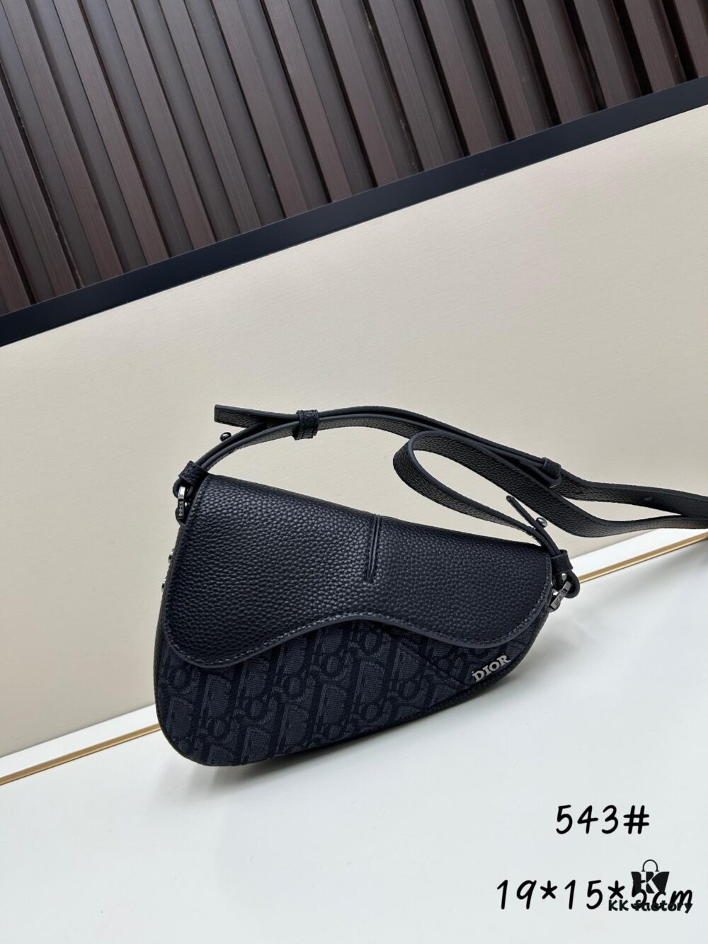 This saddle bag reinterprets the classic design with a modern structure. Crafted from beige and black Oblique printed fabric, it features a signature black grained calfskin magnetic flap and a concealed zip closure. The interior includes a large compartment and slip pockets for organizing daily essentials. This mini style comes with an adjustable and detachable leather shoulder strap, allowing for versatile wear as a handheld, shoulder, or crossbody bag.