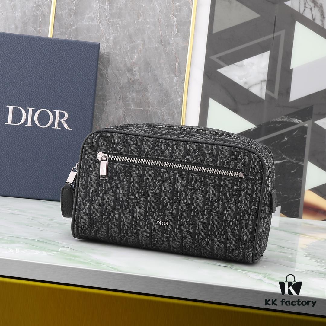 This toiletry bag combines practical functionality with minimalist design. Crafted from black Oblique-print fabric, it features grained calfskin leather trims in matching tones and is adorned with a Dior signature on the front. The front features a zip pocket, a spacious main zipped compartment, and two slip pockets. Equipped with a leather handle, it can be carried by hand or stored inside various handbags.