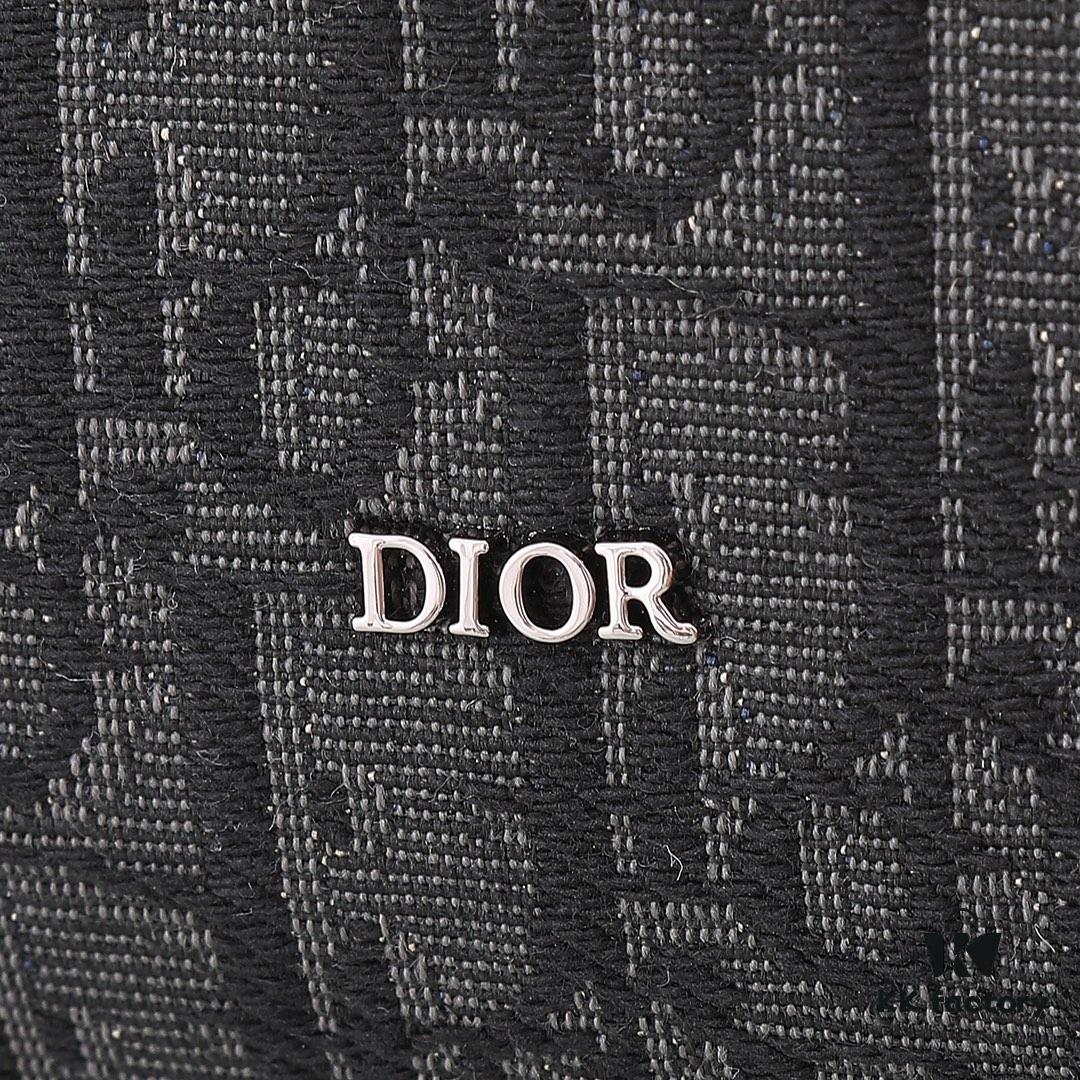This toiletry bag combines practical functionality with minimalist design. Crafted from black Oblique-print fabric, it features grained calfskin leather trims in matching tones and is adorned with a Dior signature on the front. The front features a zip pocket, a spacious main zipped compartment, and two slip pockets. Equipped with a leather handle, it can be carried by hand or stored inside various handbags.