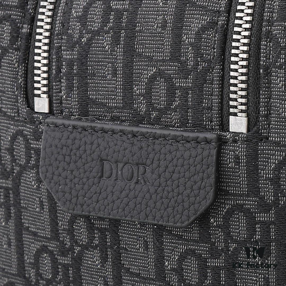 This toiletry bag combines practical functionality with minimalist design. Crafted from black Oblique-print fabric, it features grained calfskin leather trims in matching tones and is adorned with a Dior signature on the front. The front features a zip pocket, a spacious main zipped compartment, and two slip pockets. Equipped with a leather handle, it can be carried by hand or stored inside various handbags.